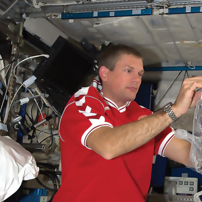 An astronaut on the space station works with the prototype water purification system based on membranes infused with aquaporins