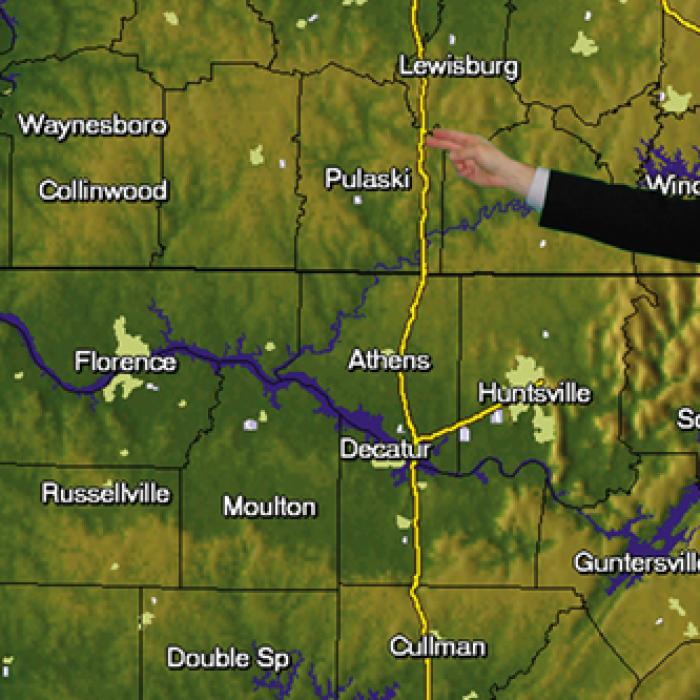 A meteorologist interacts with a map