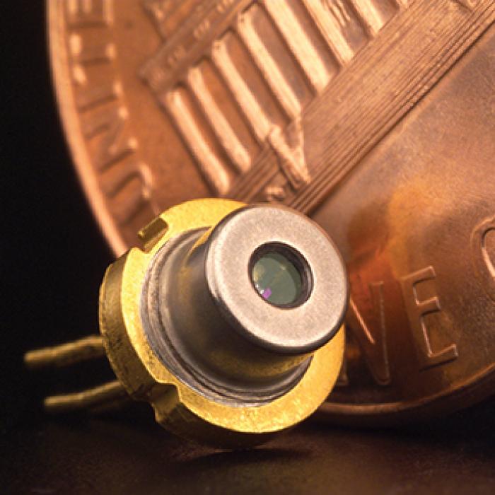 Miniaturized tunable diode laser next to a much larger but actual size penny