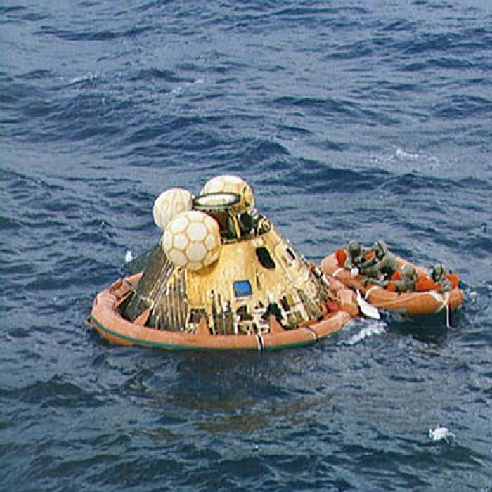 Apollo astronauts and a Navy frogman in biological isolation garments await pickup from a helicopter