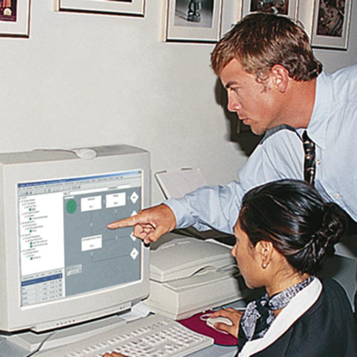Man pointing to woman's computer screen with QRAS software displayed