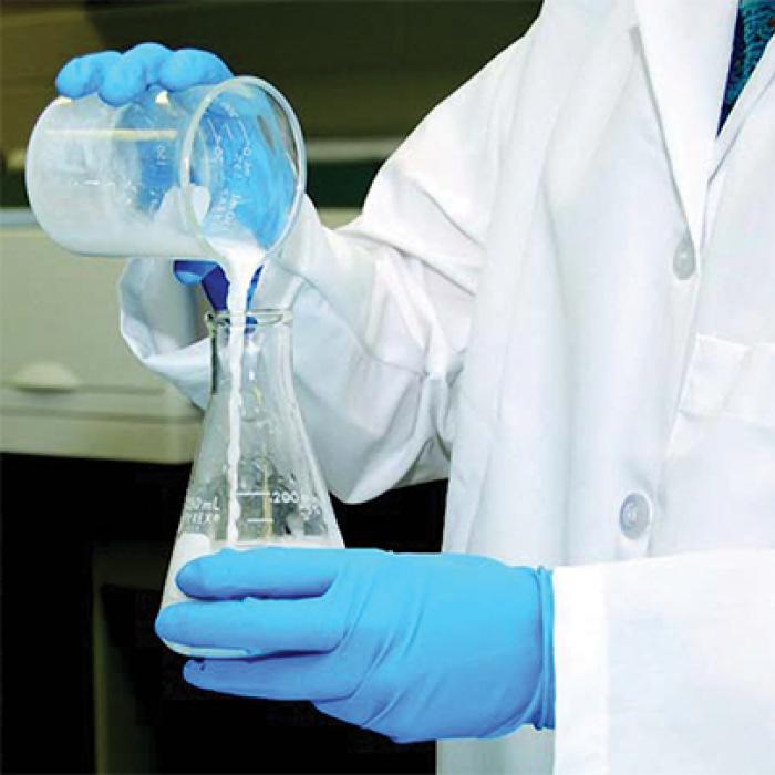 lab tech pouring clear liquid into beaker