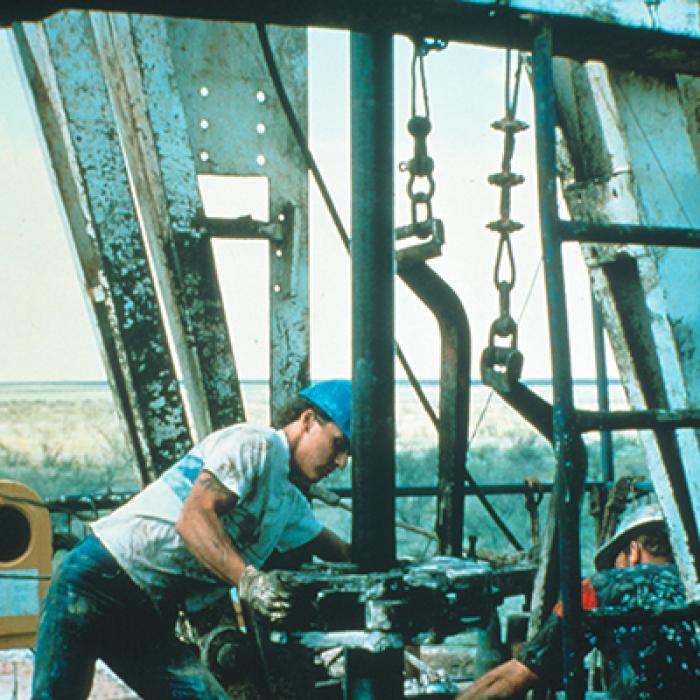 Workers at a Texaco oil field drill a vertical oil well