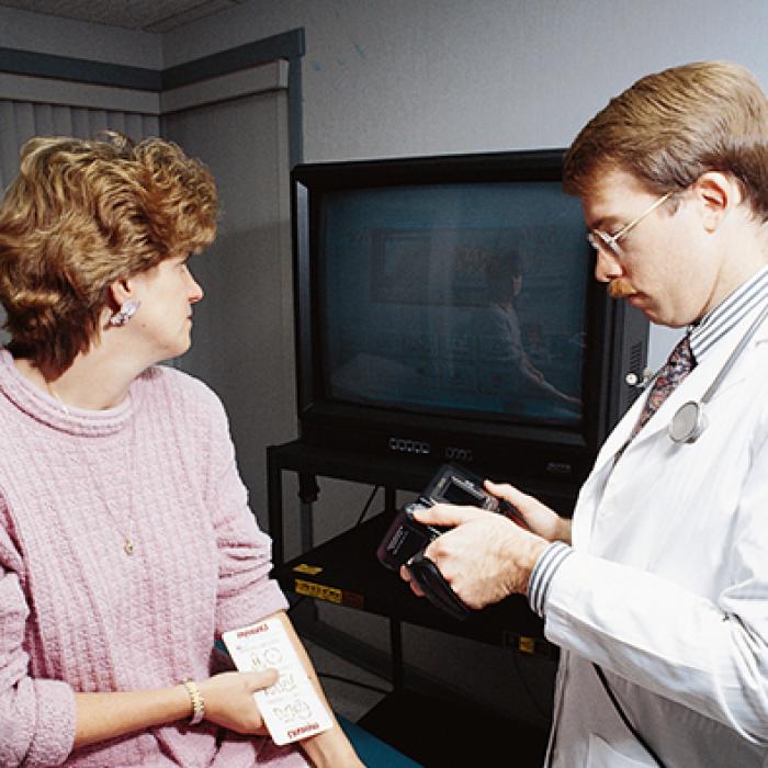 physician inspects a mole on patient's arm with a novel computerized microcomputer