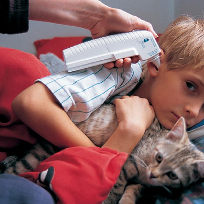 A boy has his temperature taken in ear cavity with Braun's temperature sensor