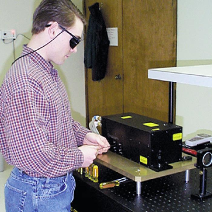 Worker wearing protective glasses and using a laser system