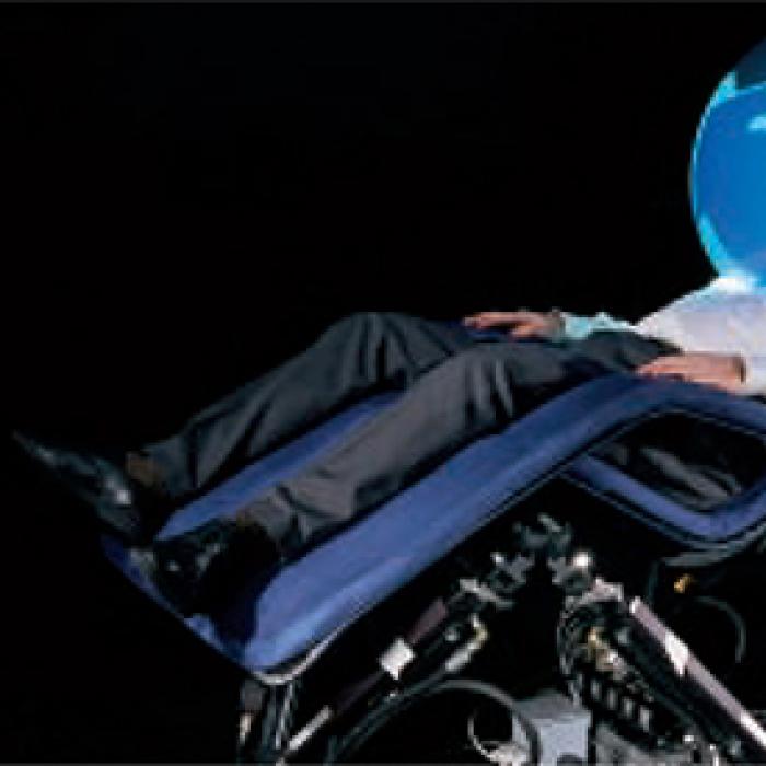 A man sits in a relaxation chair with his head inside of a bubble dome