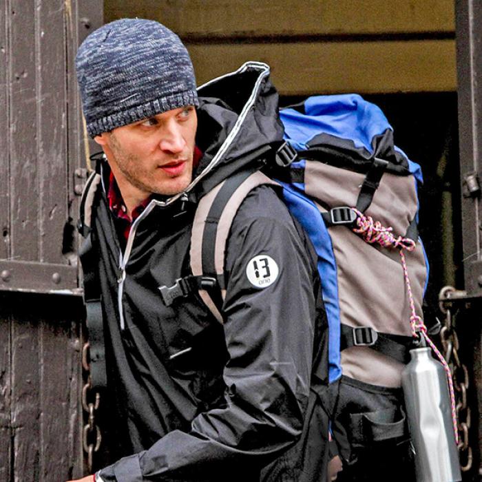 A hiker wears a 13-One jacket