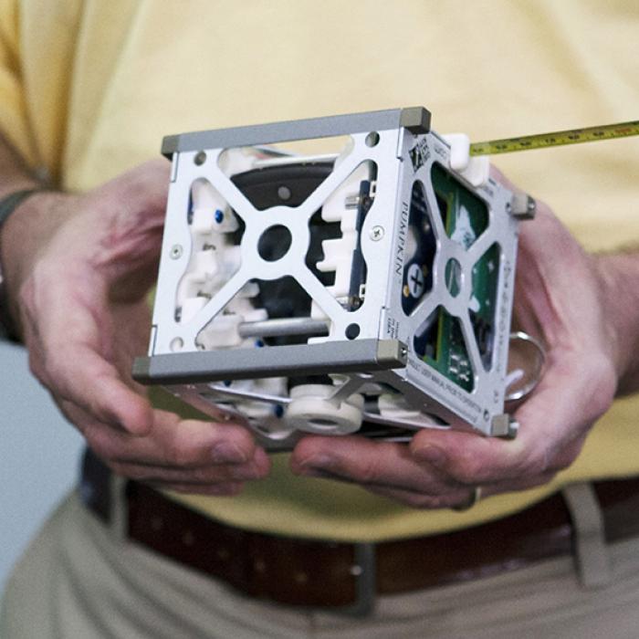 A CubeSat held in a man's hands