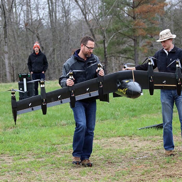 A battery-powered prototype drone, called Greased Lightning, carried by engineers David North (left) and Bill Fredericks (right)