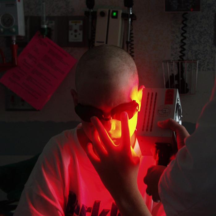 A doctor using a light-therapy device on a patient