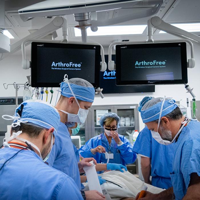 A crowded operating room with ArthroFree on screens