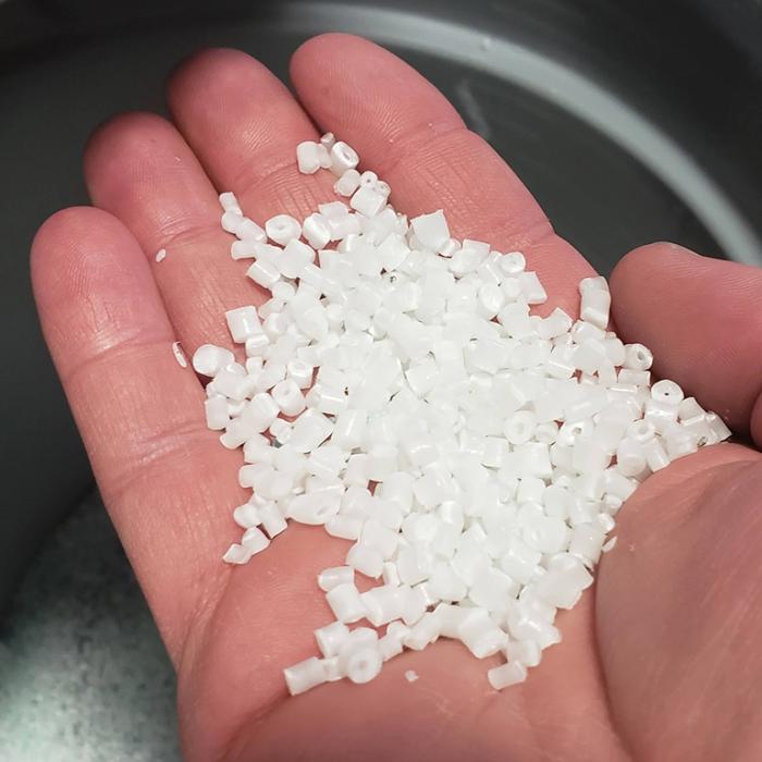 Tiny pellets of Okhata aerogel-infused plastics held in a person's hand