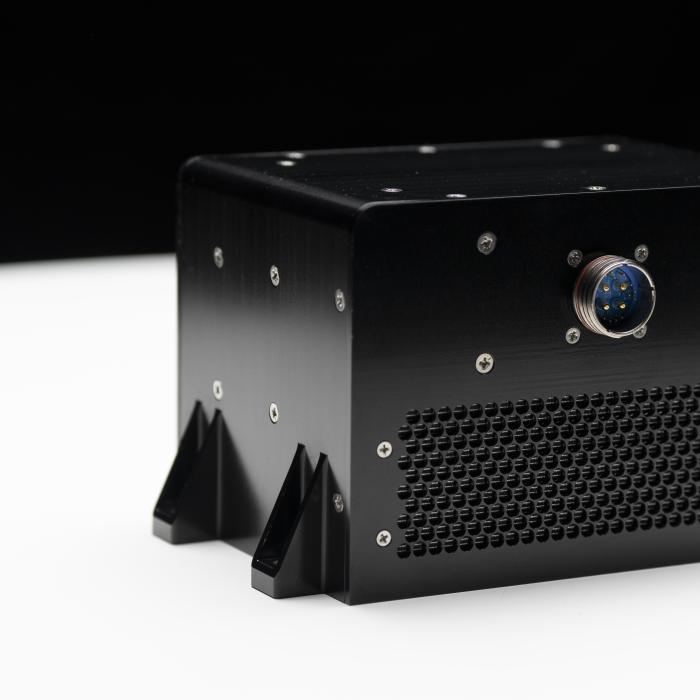 A black metal box covered in screws and with a single computer connector point.