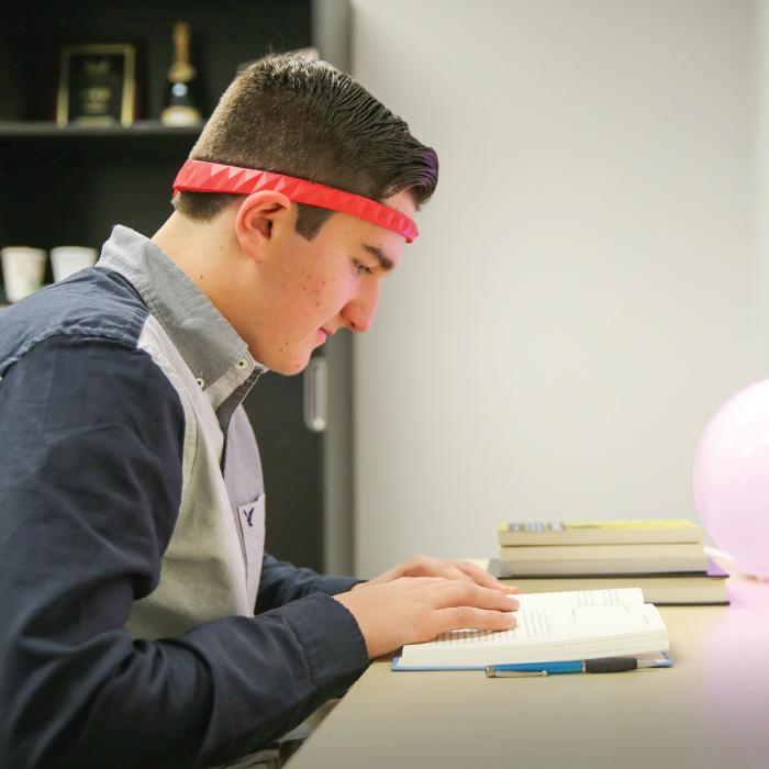 A student reading while wearing BrainCo’s LUCY headband