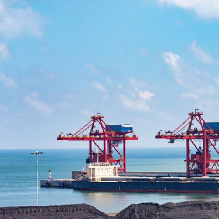 Three red steel structures on water behind black hills of a coal mine