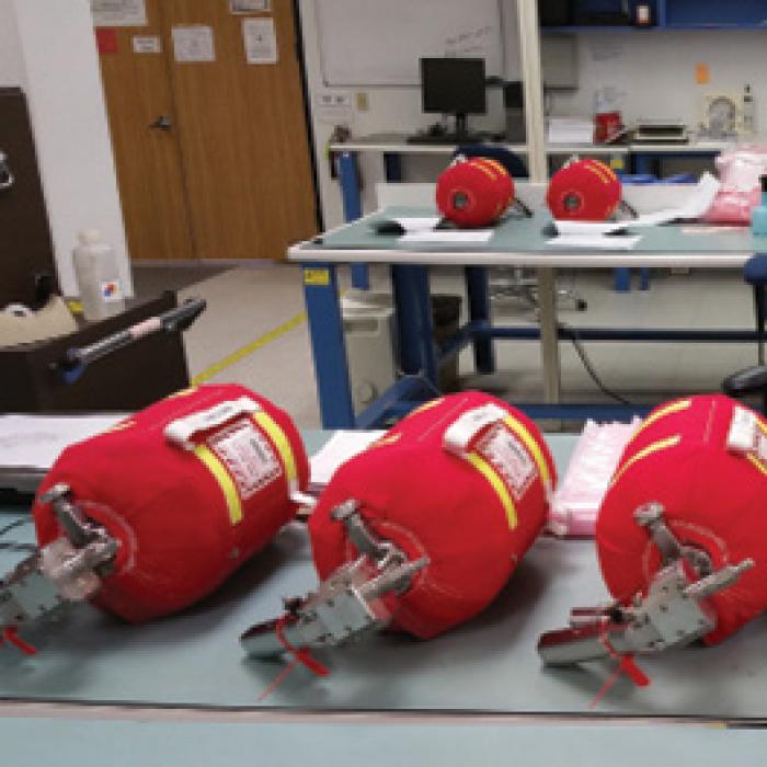Red fire extinguishers lie in a row on a table in a lab