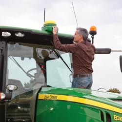 Man installing GPS navigation device on John Deere tractor