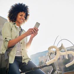 A woman sitting on a bike uses her smartphone