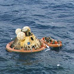 Apollo astronauts and a Navy frogman in biological isolation garments await pickup from a helicopter