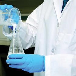 lab tech pouring clear liquid into beaker