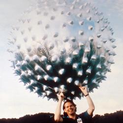 A man holding the Jimsphere, which looks like a large spiny metallic ball, above his head