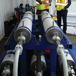 Two men with reflective safety vests standing near SureShear chambers