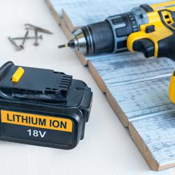 A lithium-ion 18-volt battery next to a cordless drill
