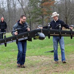 A battery-powered prototype drone, called Greased Lightning, carried by engineers David North (left) and Bill Fredericks (right)