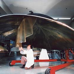 An engineer works on a Voyager spacecraft’s high-gain antenna dish